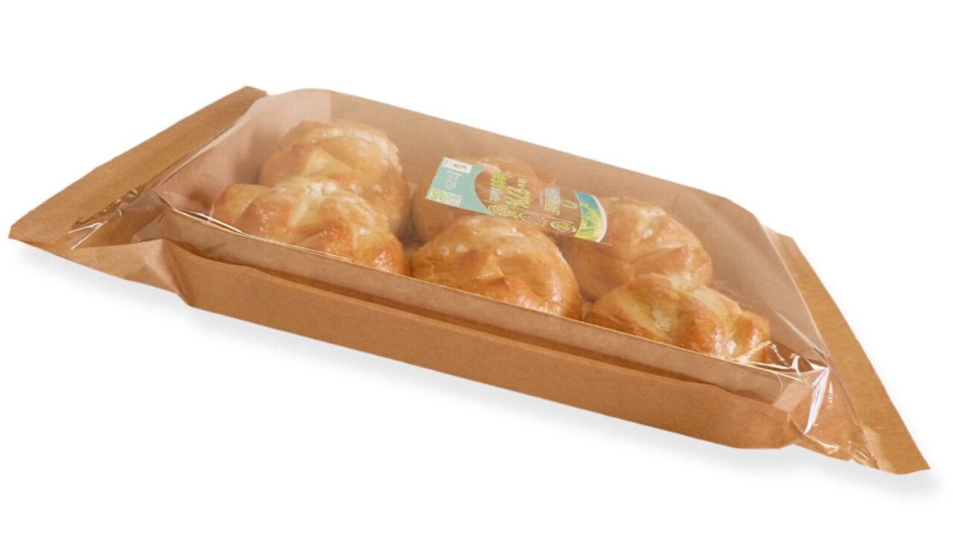 Ein rechteckiges braunes Papiertablett mit einem durchsichtigen Plastikdeckel enthält sechs runde Brötchen, ordentlich angeordnet und teilweise durch die Verpackung sichtbar.