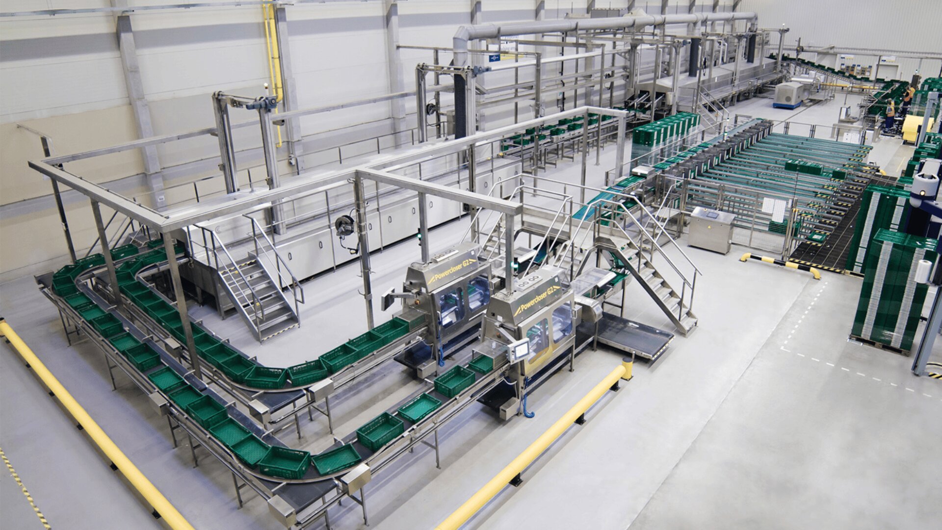 Eine moderne automatisierte Fertigungsstraße in einer Fabrik mit Förderbändern, Maschinen und Metallstrukturen in einem großen, sauberen Industriebereich. Es sind keine Arbeiter zu sehen.