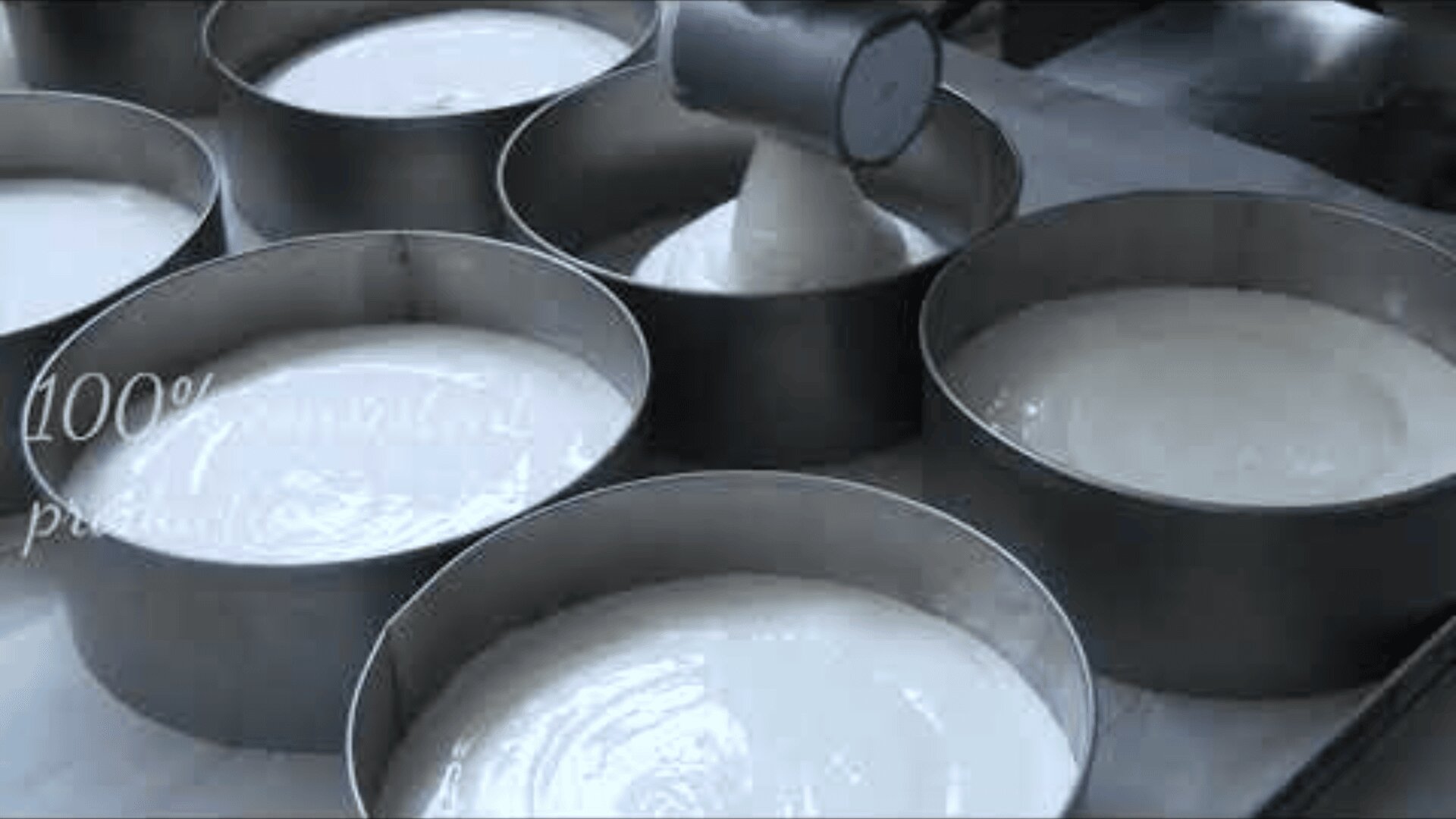 Kuchenteig, der in mehrere runde Metallbackformen gegossen wird und diese gleichmäßig füllt, um das Backen vorzubereiten.