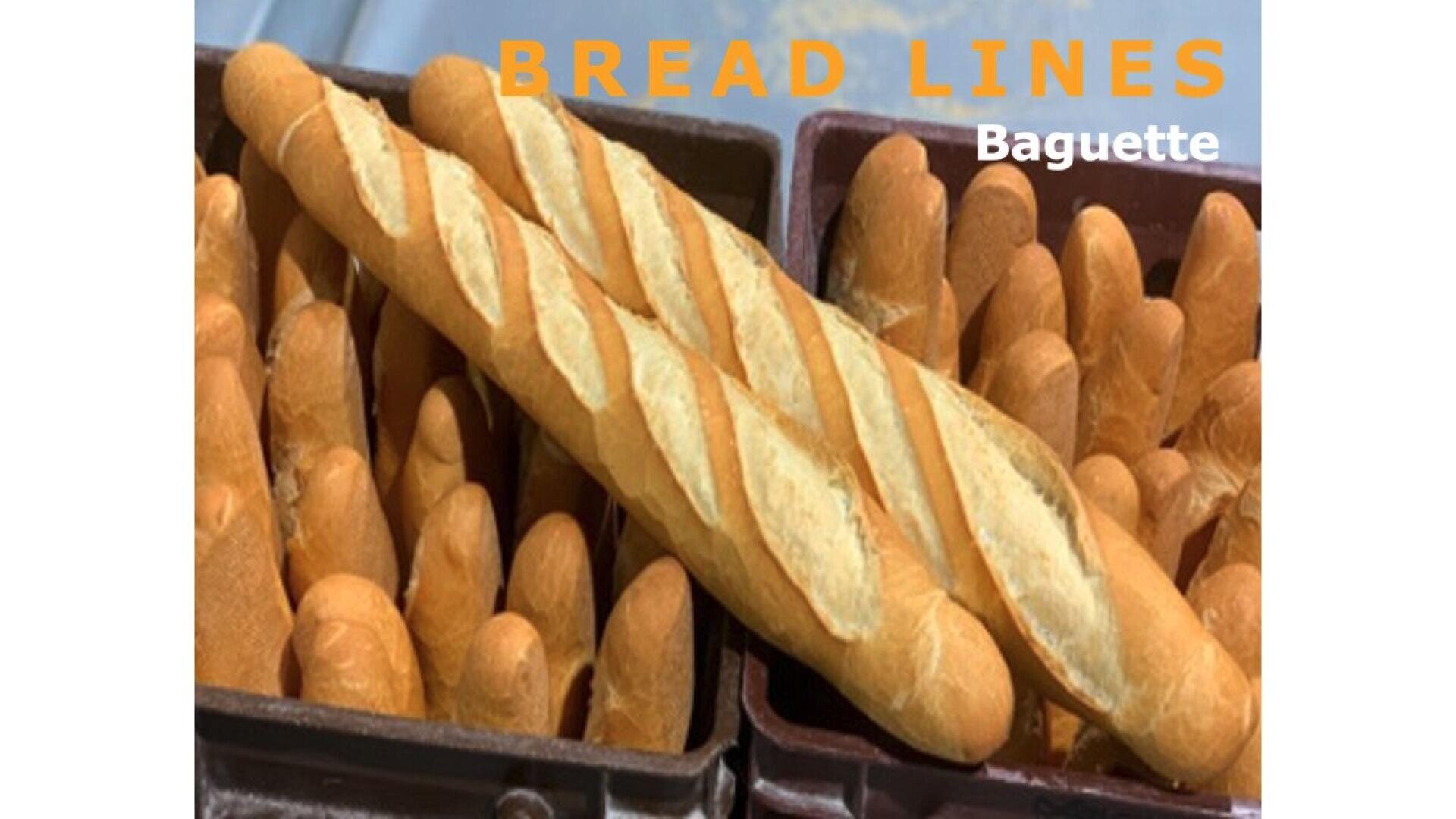 Mehrere goldbraune Baguettes sind in Schalen angeordnet, wobei ein großes Baguette diagonal darauf liegt. Der Text BREAD LINES und Baguette erscheint in der oberen rechten Ecke.
