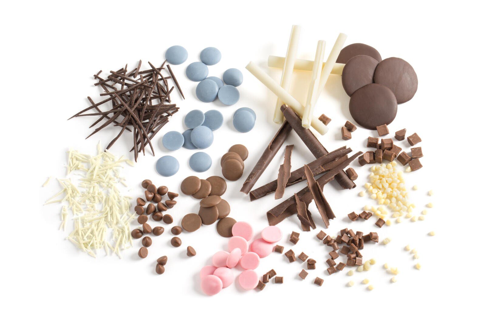 Eine Auswahl an Schokoladendekorationen und Süßigkeiten in verschiedenen Formen, Größen und Farben, darunter Raspeln, Stäbchen, Chips, Locken und Scheiben, angeordnet auf einem weißen Hintergrund.