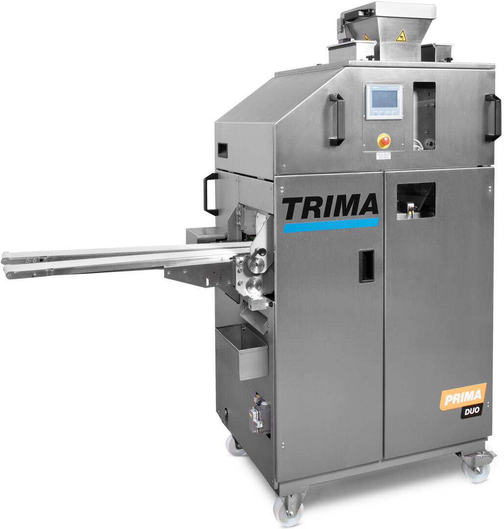 A stainless steel industrial bread or dough processing machine labeled TRIMA PRIMA DUO, featuring a digital control panel, side arms, and mounted on wheels for mobility.
