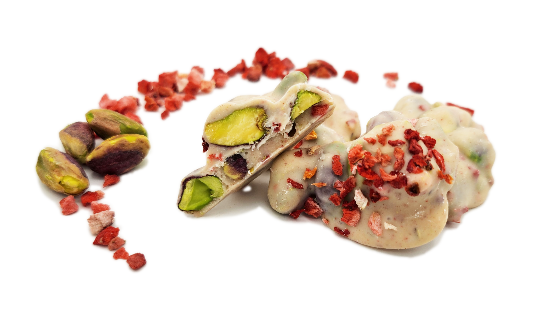 Weiße Schokoladenhäufchen mit ganzen Pistazien und getrockneten Erdbeerstücken, umgeben von losen Pistazien und verstreuten Stücken getrockneter Erdbeeren auf weißem Hintergrund.