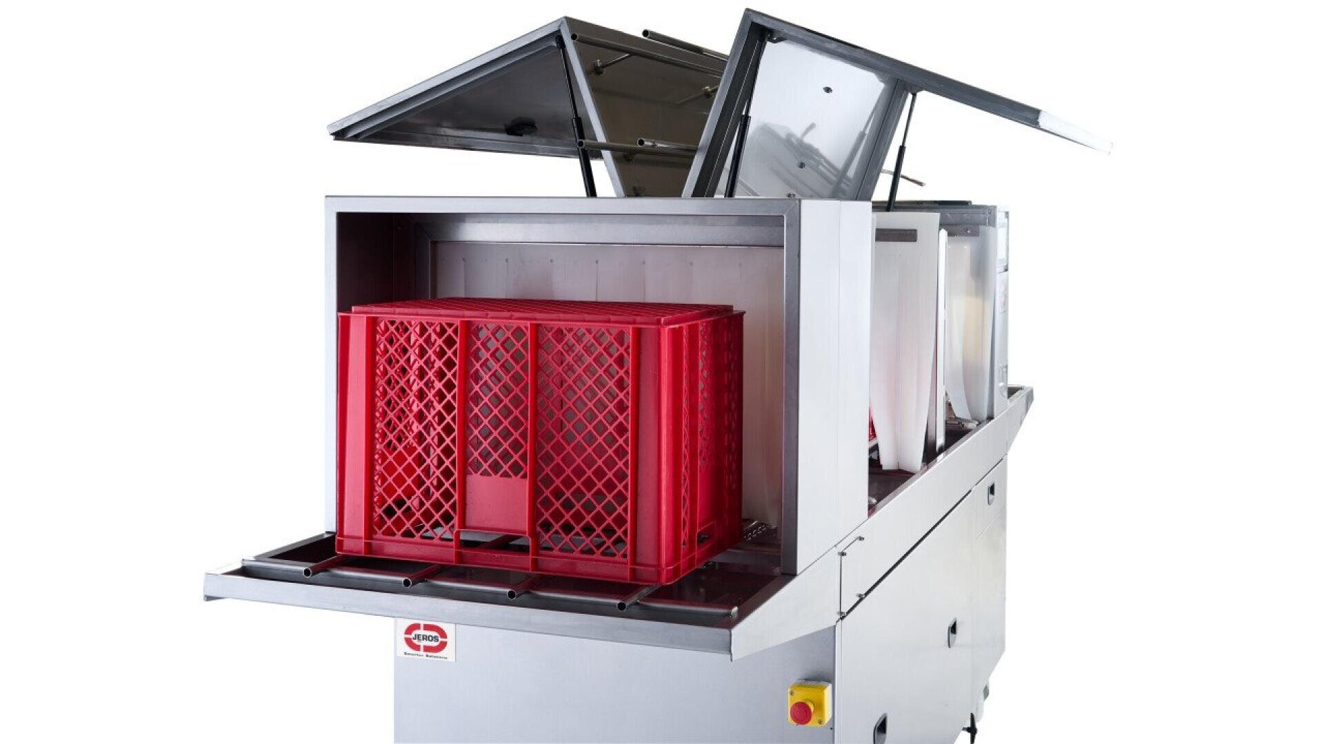 A commercial dishwasher with its top panels open, showing a red plastic crate loaded inside on a steel rack, ready for washing. The machine is silver and industrial, with a visible control button on the front corner.