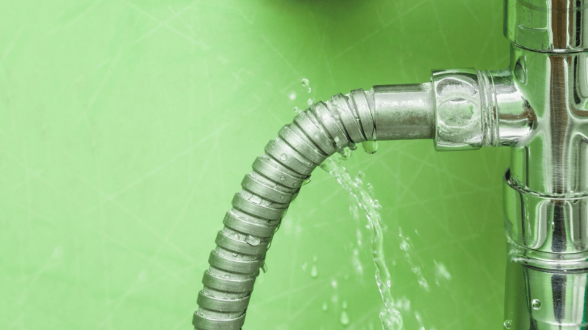 Ein Metallrohr mit einem flexiblen Abschnitt weist vor einem hellgrünen Hintergrund einen Wasseraustritt auf. Wasserströme treten sichtbar aus der Verbindung aus.