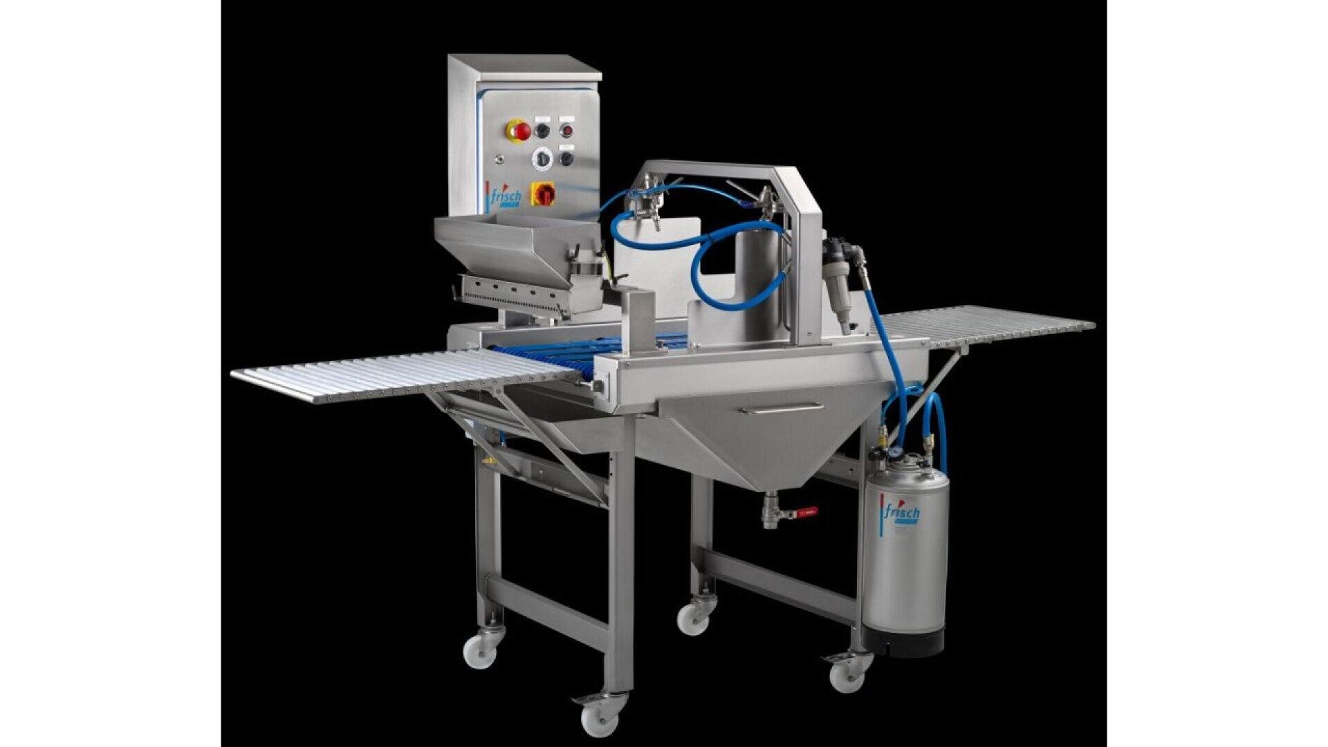 A stainless steel industrial food processing machine with control panel, conveyor belt, hoses, and wheels, designed for automated production, set against a black background.