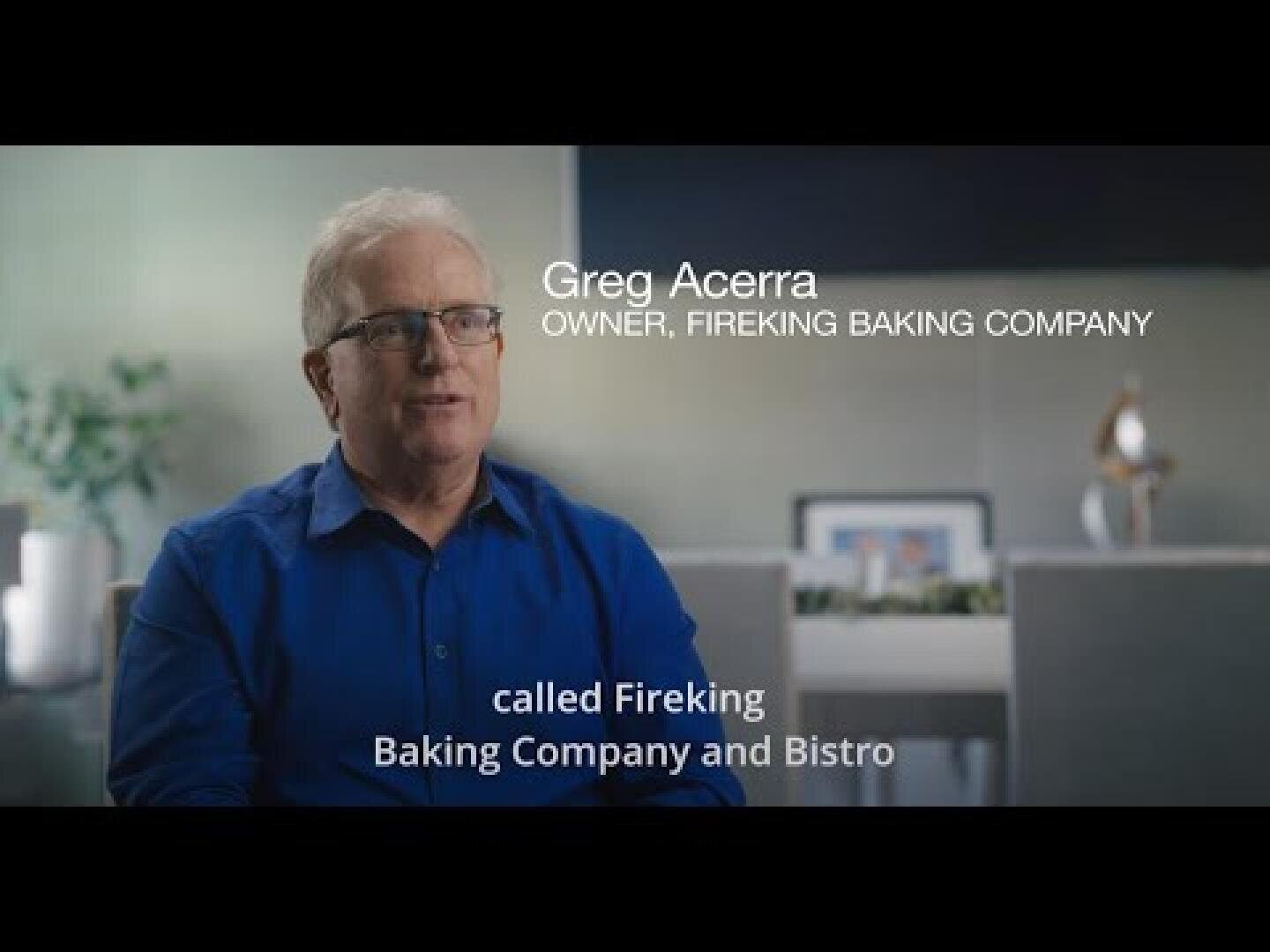 A man in a blue shirt sits indoors, with text on the image that reads: Greg Acerra, Owner, Fireking Baking Company, and below, called Fireking Baking Company and Bistro. The background is softly blurred.