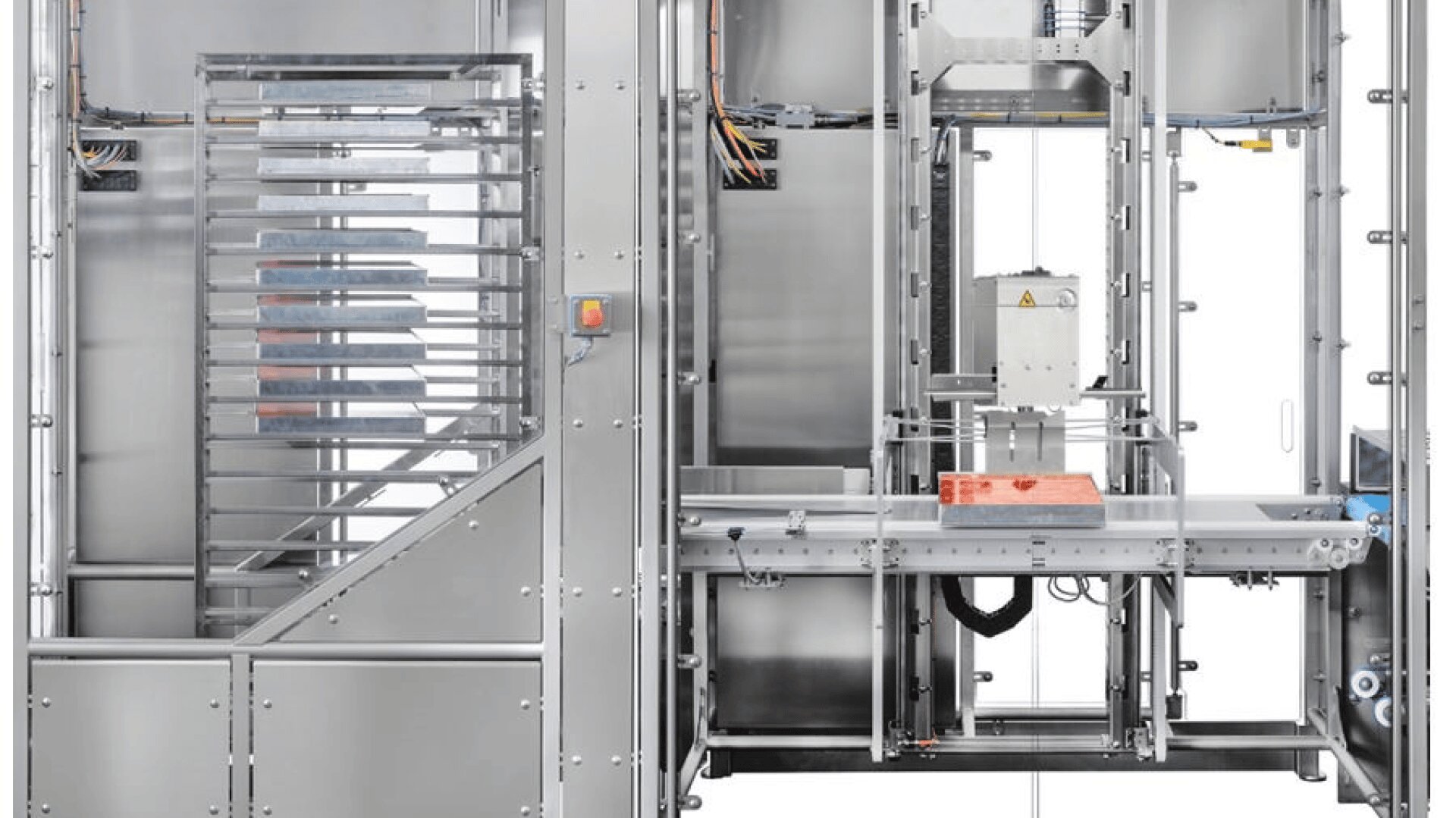 Industrielle Verpackungsmaschine aus rostfreiem Stahl mit Förderbändern und Schutzplatten, die eine rote Verpackung in einem transparenten Gehäuse mit sichtbarer Verkabelung und mechanischen Komponenten verarbeitet.