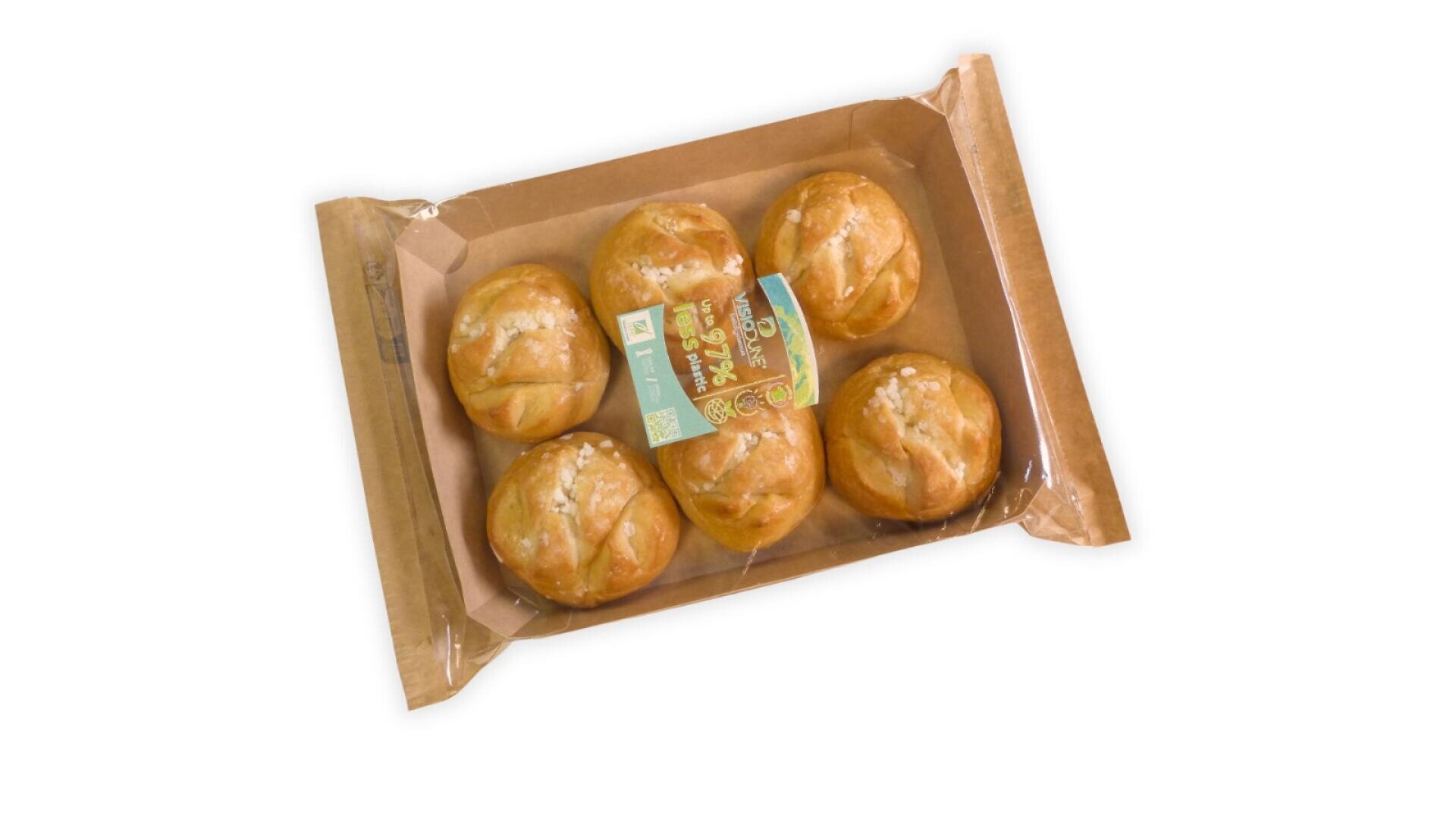 A brown paper tray containing six round bread rolls with a golden crust, sealed with clear plastic and a label on top, placed on a white background.