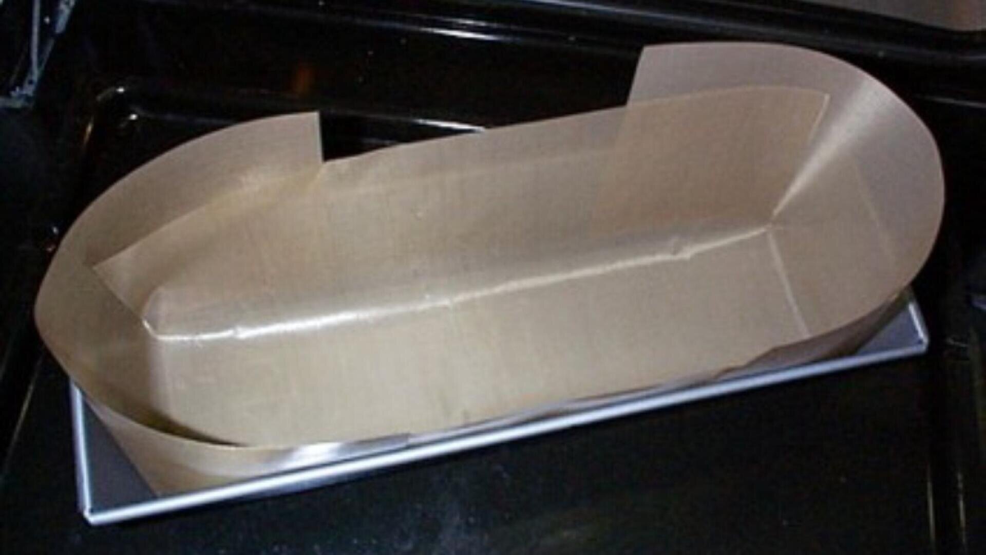 A rectangular metal baking pan lined with parchment paper that extends above the edges, shaped to fit the pan and ready for use.
