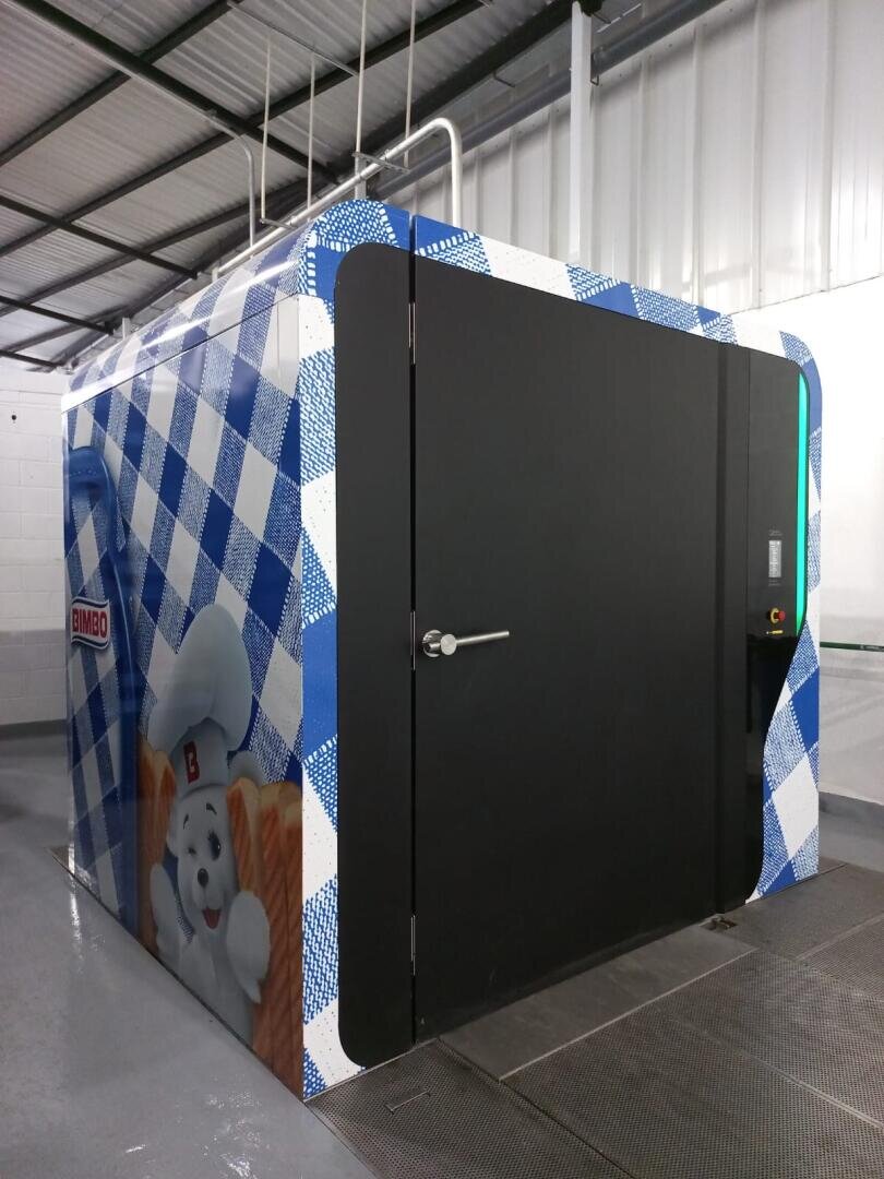 Large industrial oven or baking chamber with blue checkered pattern and Bimbo bear mascot on the side, situated in a clean, modern facility with metal ceiling and gray floor.