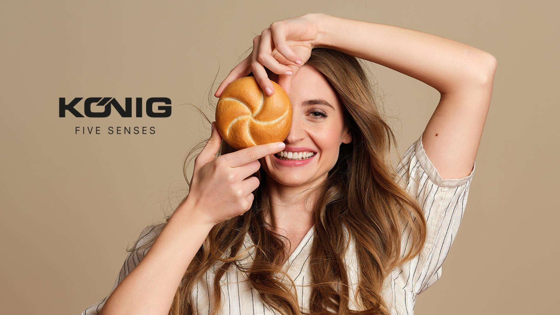 Eine lächelnde Frau hält ein rundes Brötchen vor ein Auge, die andere Hand hält sie über den Kopf. Neben ihr erscheint der Text König Five Senses auf einem beigen Hintergrund.