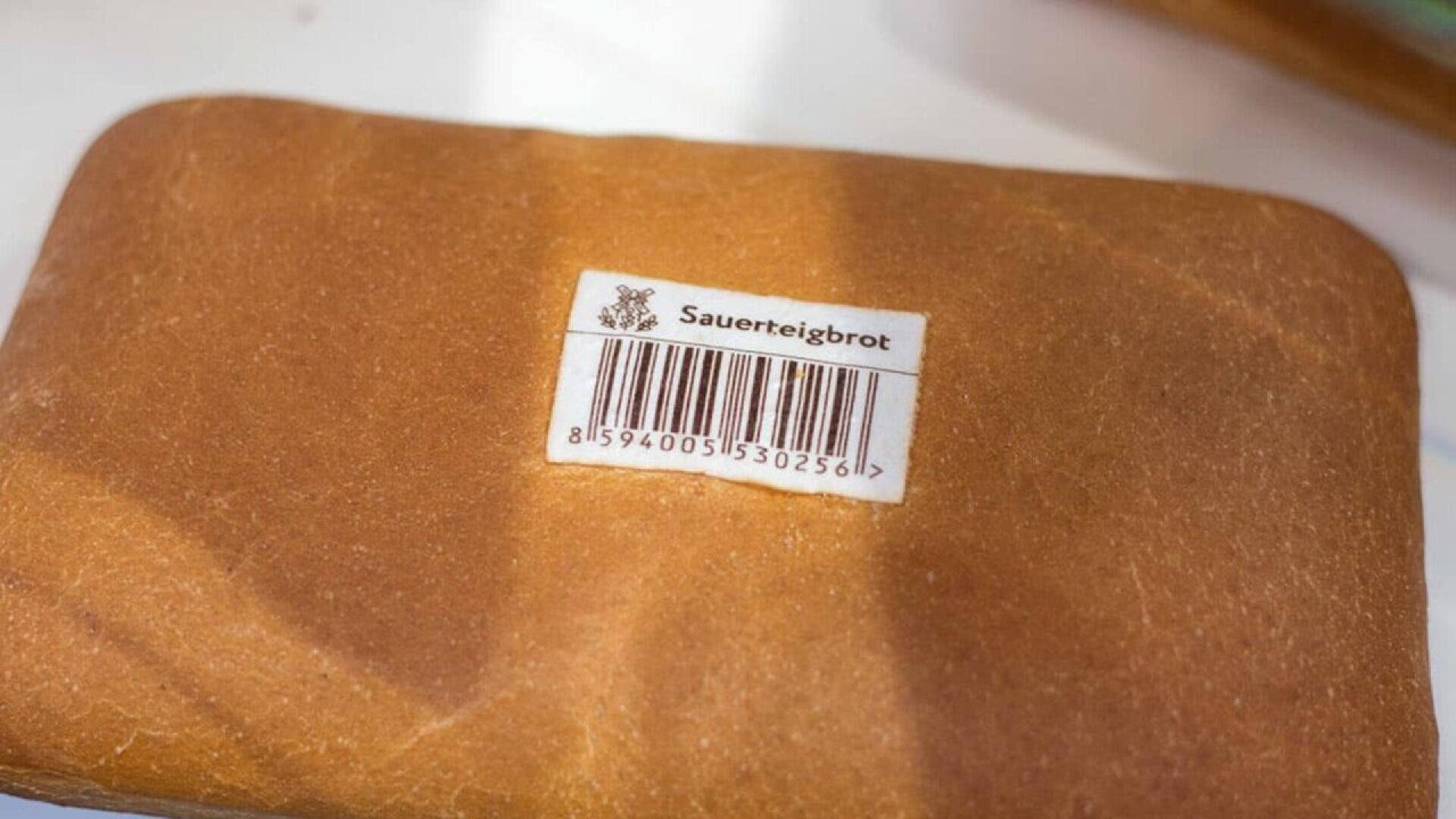 Ein Laib Brot mit einem Aufkleber mit der Aufschrift Sauerteigbrot und einem Strichcode auf einer weißen Fläche.