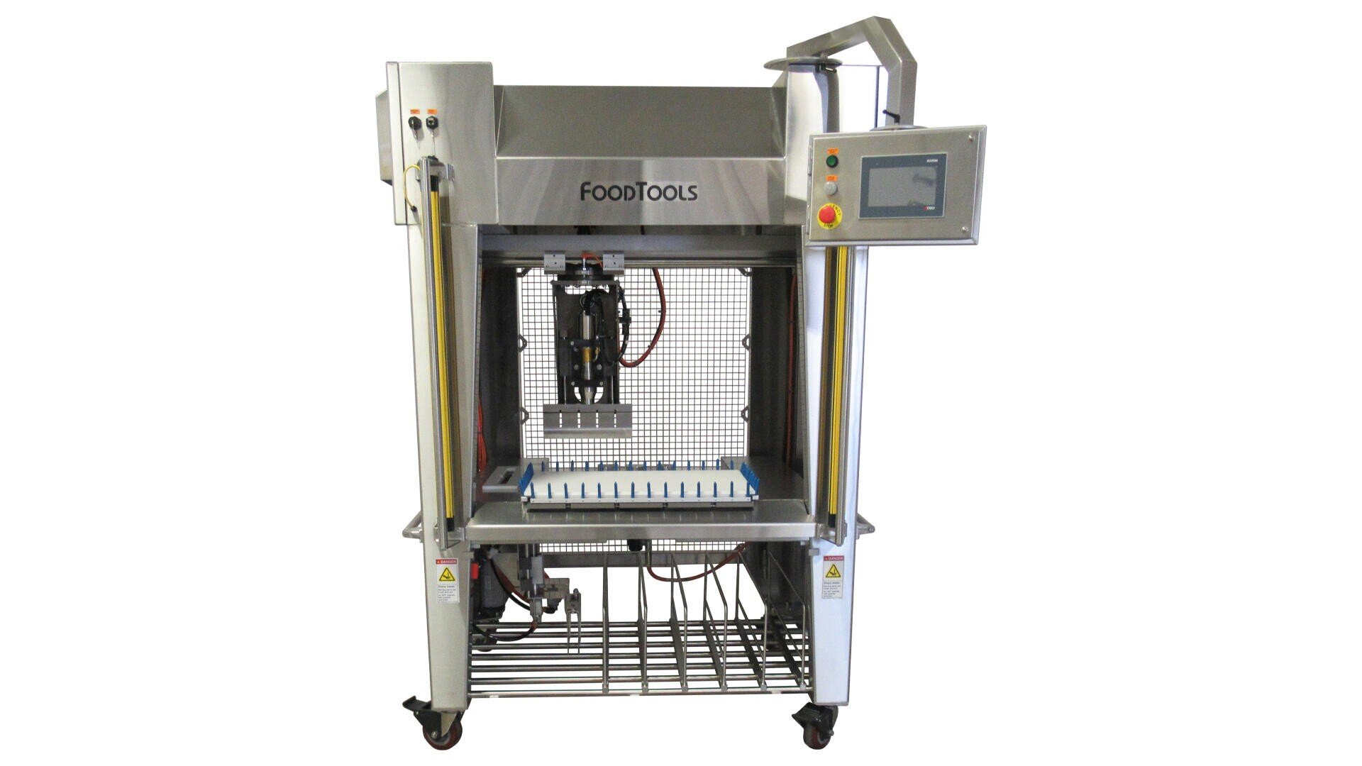 A stainless steel industrial food slicing machine with a control panel on the right, grid-like cutting area in the center, and wheels at the base for mobility. The brand FoodTools is displayed on the machine.