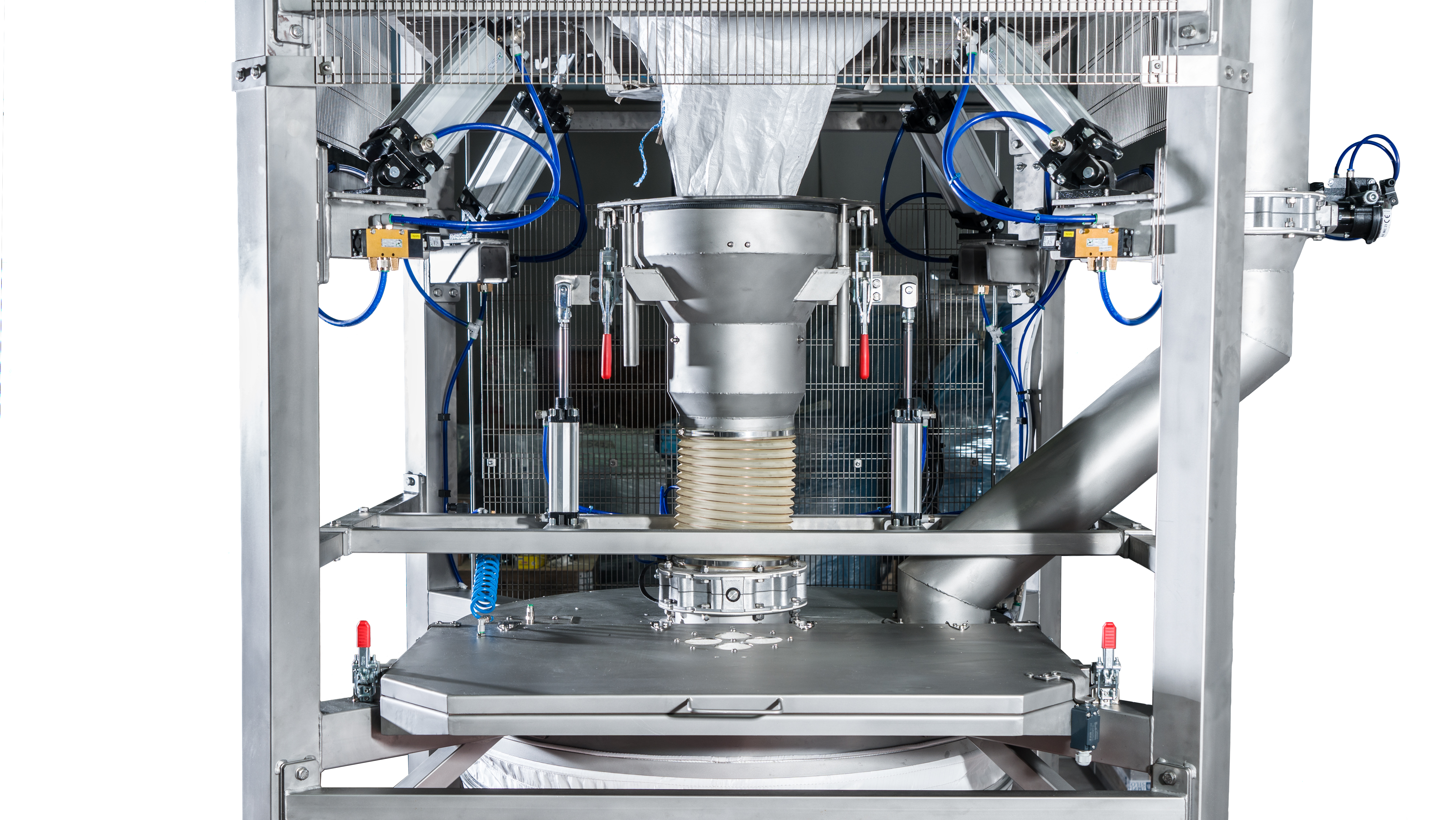 Front view of an industrial stainless steel machine with mechanical arms, tubing, and a central funnel, used for processing or packaging materials, against a white background.