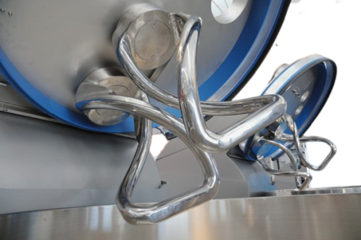Close-up of large, shiny, intertwined metal dough hooks attached to industrial mixing machines, commonly used in commercial bakeries for mixing large batches of dough.